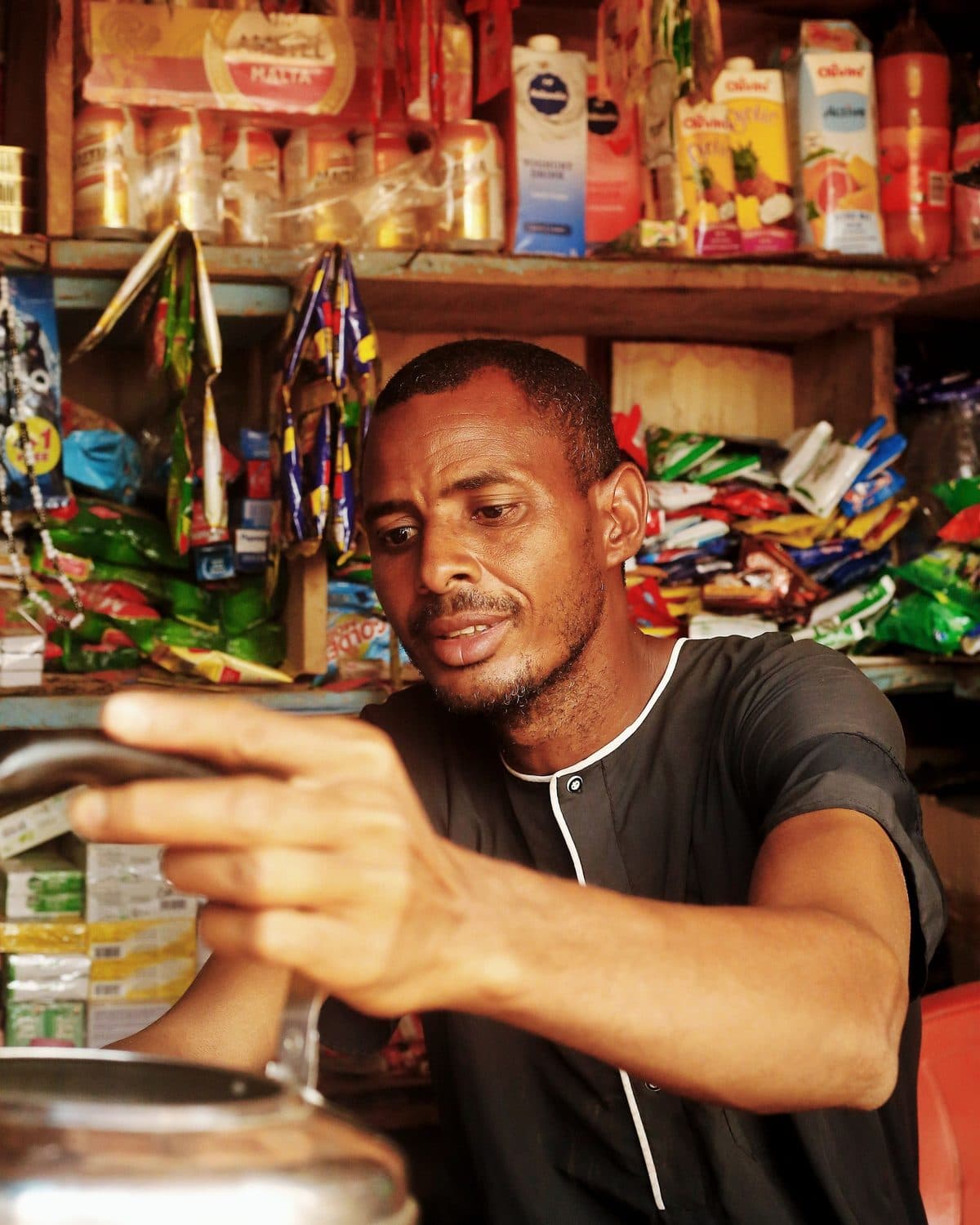 A shopkeeper in his store, reaching for his shelves.